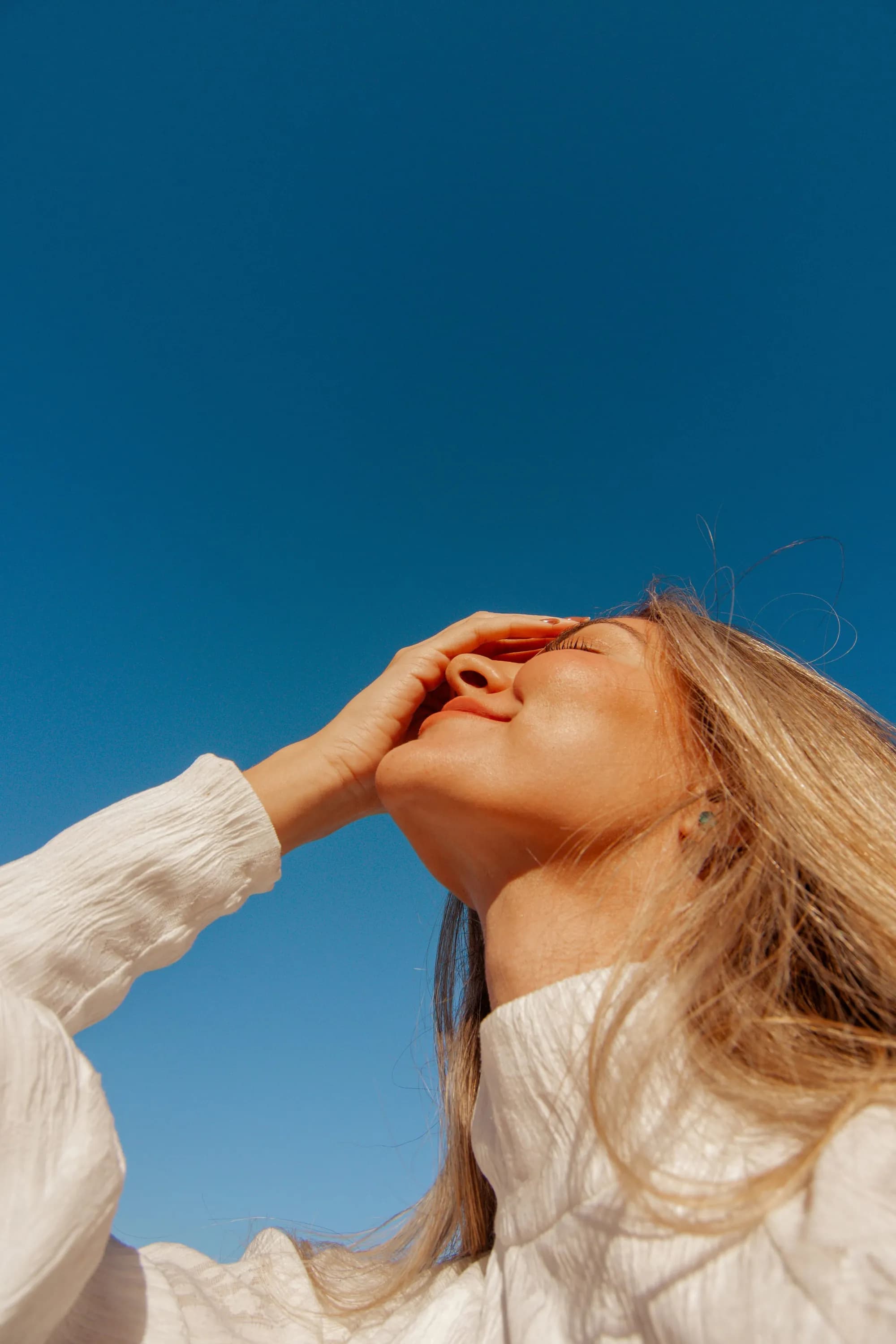 Woman running a hand through her hair in golden hour light