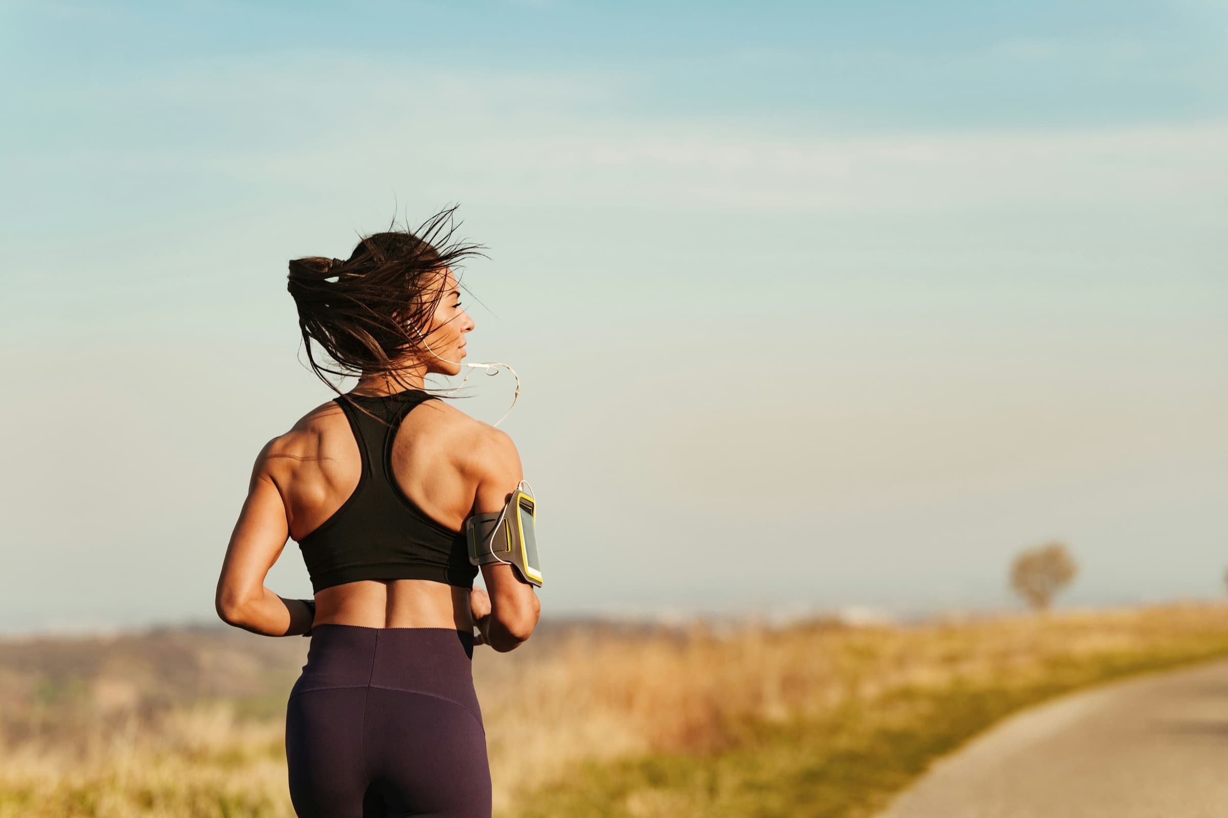 Woman running outdoors listening to earbuds